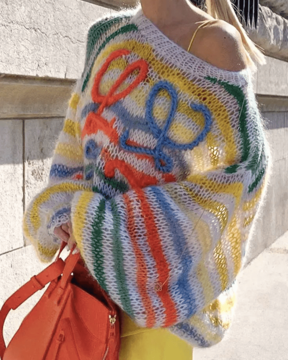 Side view of the Confetti Loewe Knit styled with yellow pants and a bright
orange handbag, high-fashion editorial vibe.