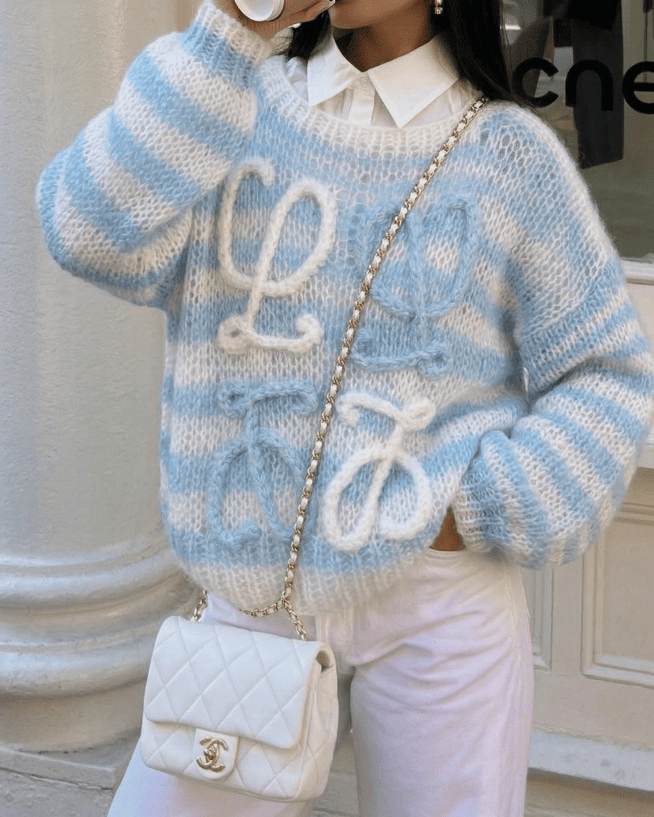  Elegant styling of the Ciel Blue Loewe Knit layered over a white button-down shirt with a quilted luxury-style bag.