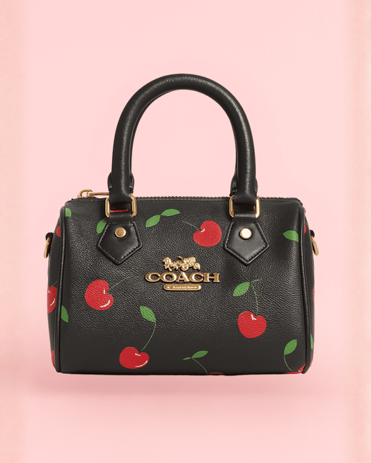 Sleek black Coach inspired mini bag with bold red cherry print and gold luxe hardware, vintage-inspired aesthetic.