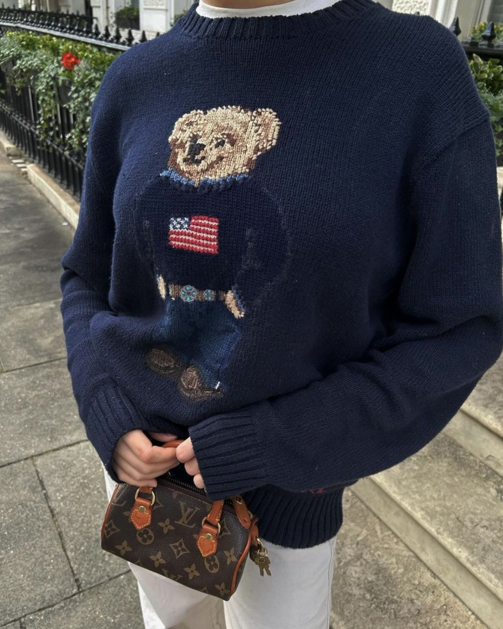 Close-up of the vintage flag and teddy bear embroidery on the navy knit sweater