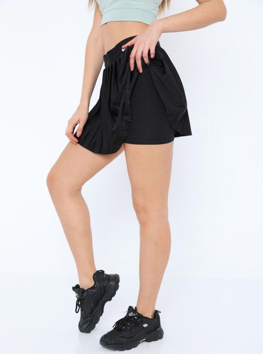 Detailed shot of the white Nike logo on a black pleated skirt,
highlighting the iconic sporty-chic finish.