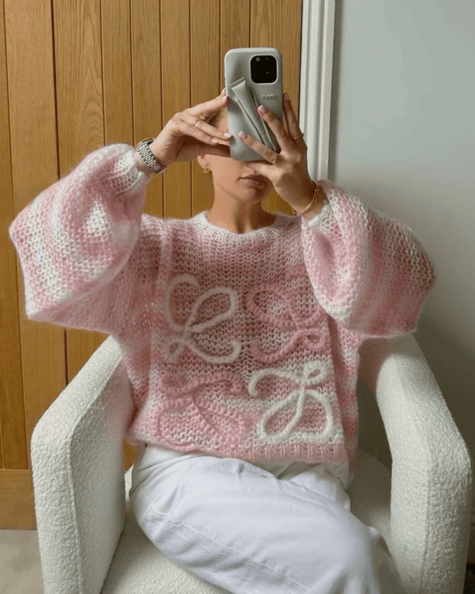 Girl styling a pink striped coquette Loewe sweater with white trousers, mirror selfie aesthetic.