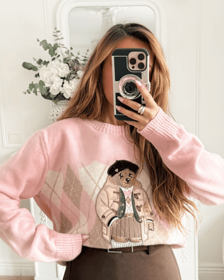 Detailed shot of the whimsical trumpet-playing bear on the pink coquette sweater.
