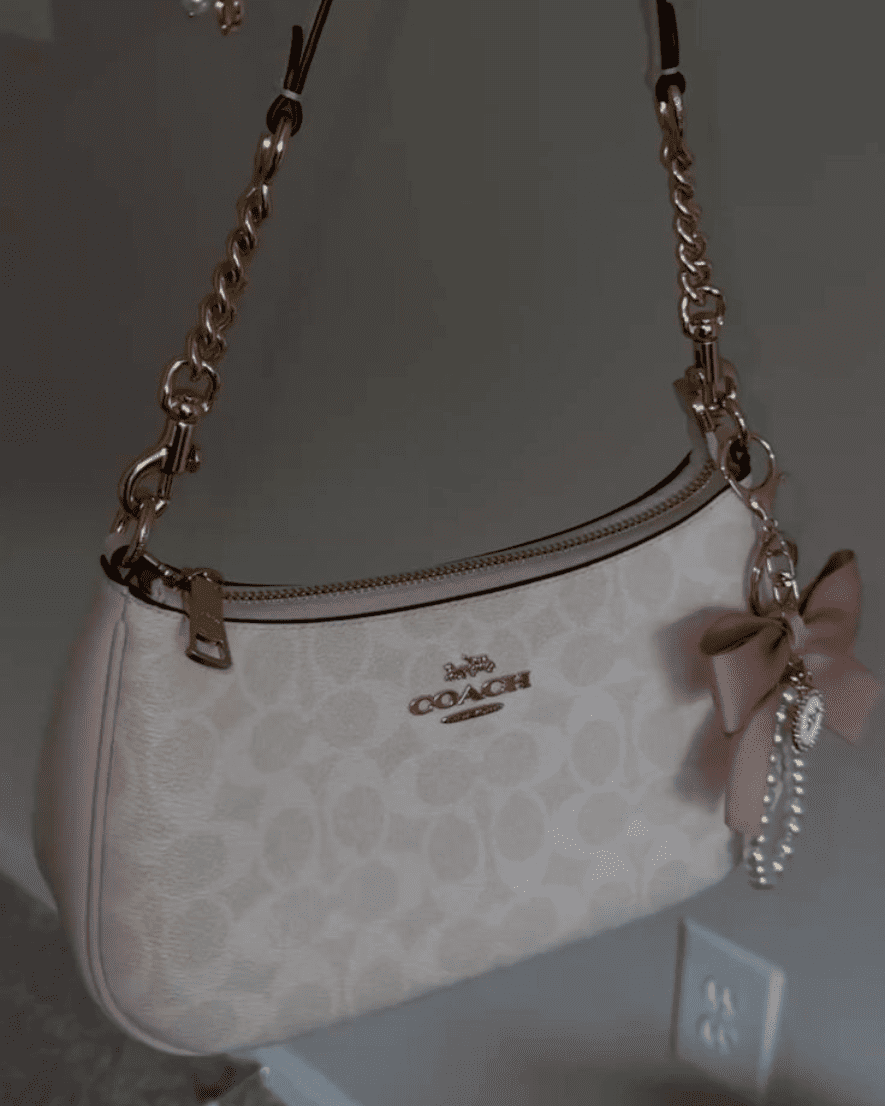 Minimalist white monogram bag hanging, showing the gold chain and Coach inspired monogram.